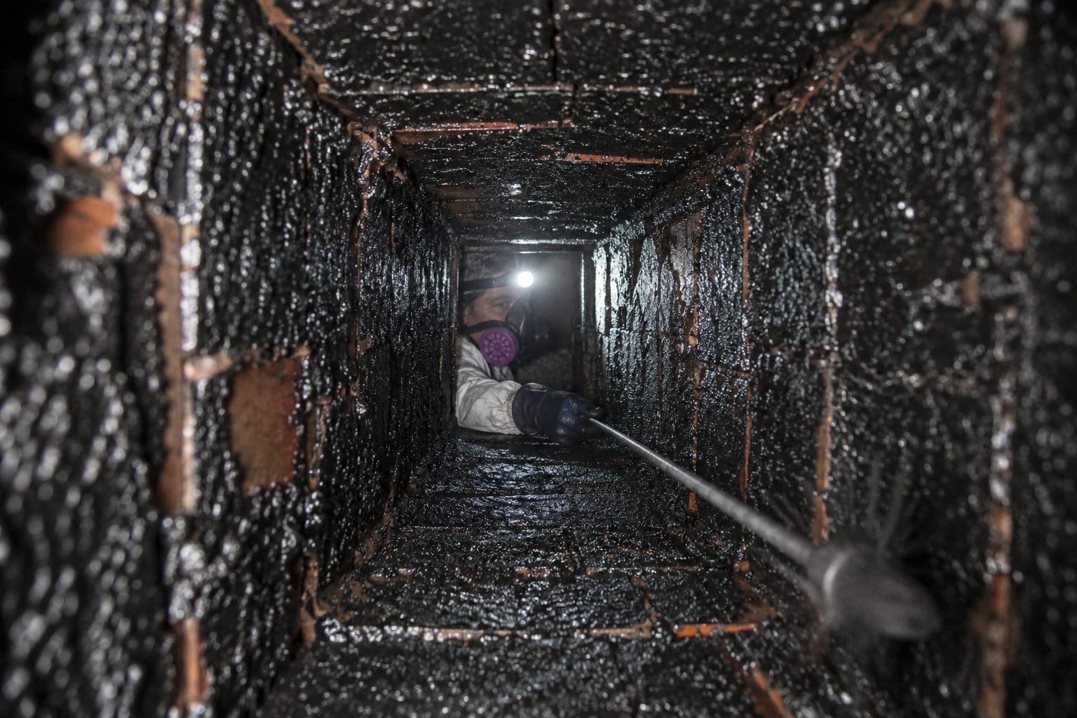 Thick glazed creosote buildup inside a wood-burning flue before chimney cleaning in Syracuse, NY