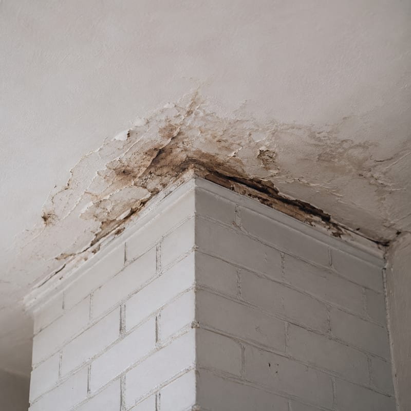 Water-stained ceiling beside a chimney breast in a Syracuse, NY home