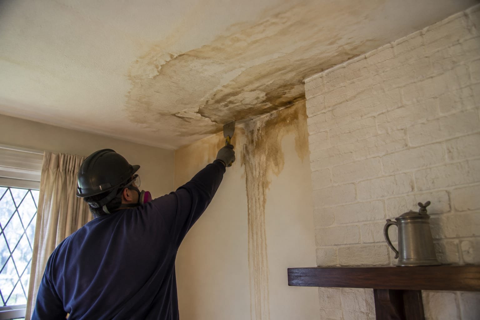 Water-stained ceiling and damaged plaster beside a chimney chase in a Syracuse, NY home